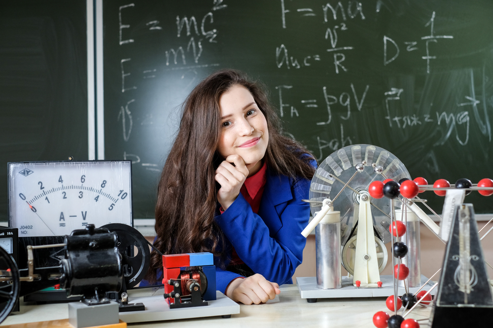 Garota que tinha dificuldade em física e conseguiu superá-las através das dicas, em uma sala de aula com equipamentos da disciplina