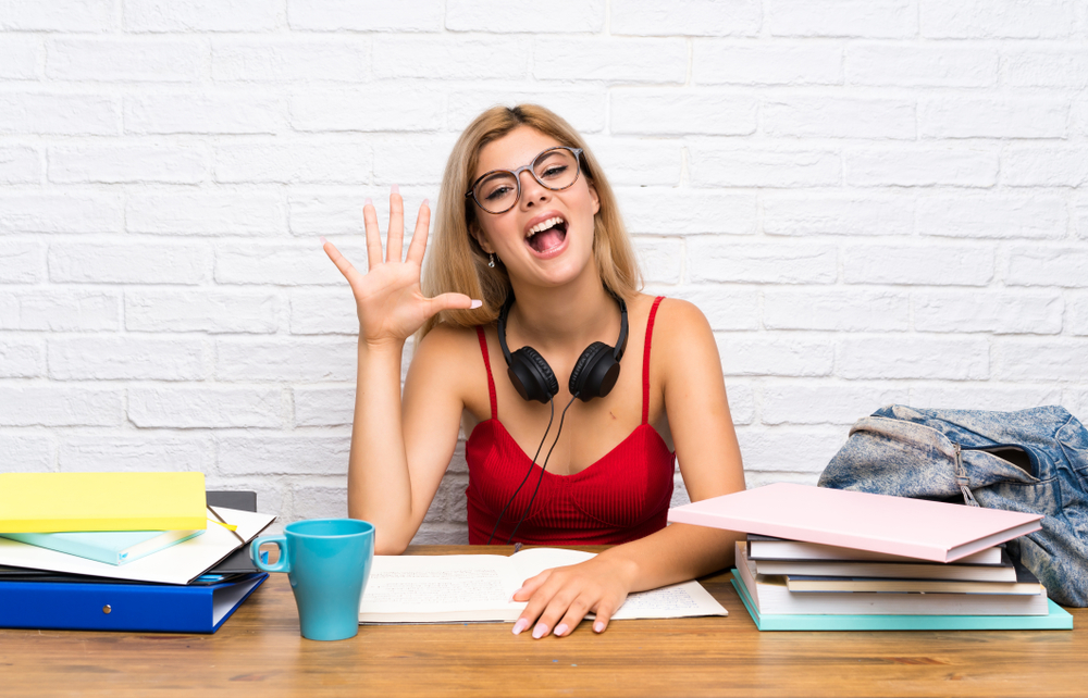 Menina estudante fazendo o número 5 com a mão, indicando o número de técnicas de aprendizagem para passar no vestibular