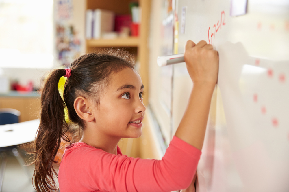 Garotinha resolvendo no quadro negro desafios matemáticos no ensino fundamental